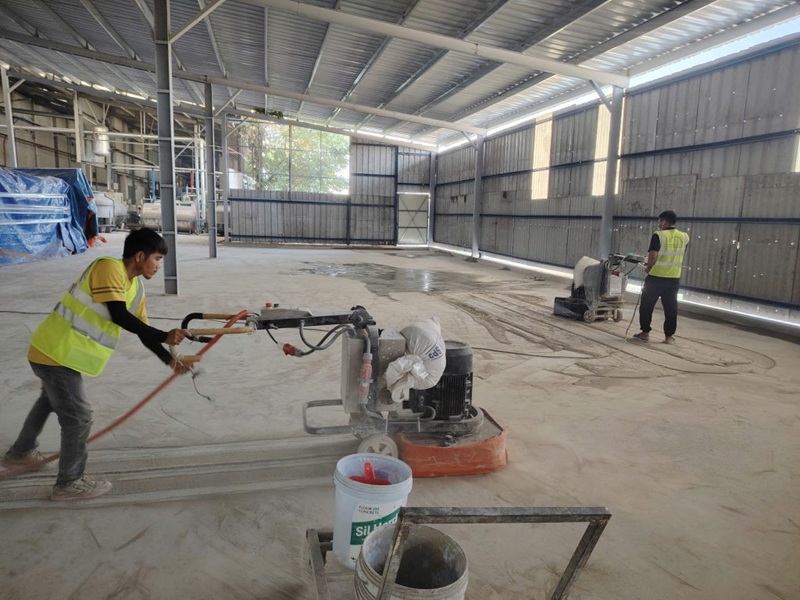 Công nhân thực hiện đánh bóng nền bê tông trong quy trình bảo trì xưởng Dầu Giây Đồng Nai, chuẩn bị bề mặt trước khi thi công sơn epoxy chống bụi và chống mài mòn.